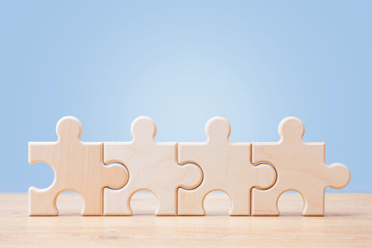 Wooden puzzle pieces connected on blue background with copy space. Teamwork, partnership and business integration concept for corporate strategy, collaboration, problem solving or workflow design.