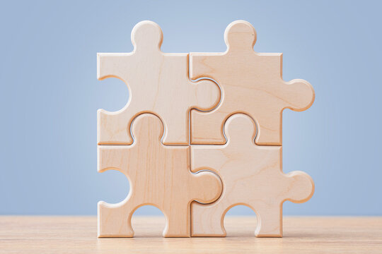 Wooden puzzle pieces connected on blue background with copy space. Teamwork, partnership and business integration concept for corporate strategy, collaboration, problem solving or workflow design.