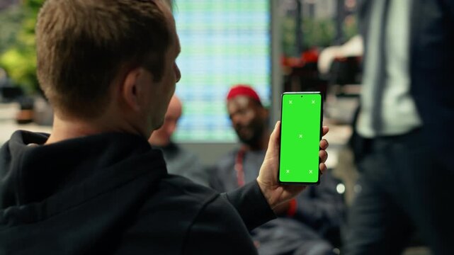 Vertical chroma key on smartphone in modern bus station with seated passengers waiting for daily commute. Diverse people on the move creates realistic public transportation activity.