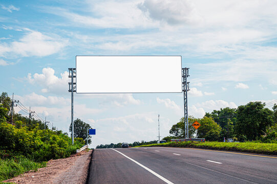 Large empty overhead billboard mockup located on rural highway road. Clear blue sky background, for outdoor advertising, marketing displays, and brand promotion.
