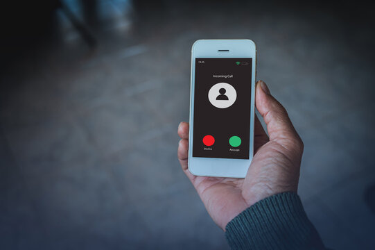 close-up of hand holding white mobile phone showing an incoming call screen with accept and decline buttons. Perfect for communication, technology, and business-related content.
