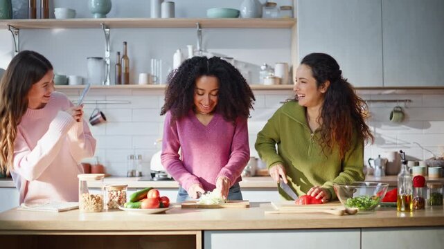 Friends recording culinary blog at kitchen. Smiling multiracial women chopping