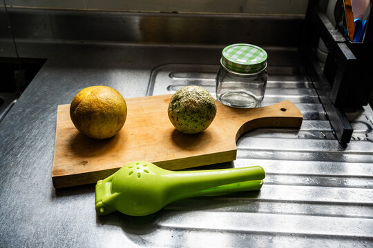 Utensilios de cocina y c&iacute;tricos sobre tabla de madera en encimera met&aacute;lica de cocina