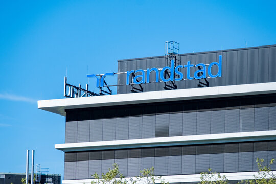 Randstad logo modern office building, Dutch HR agency, staffing solutions, temporary work, trust uncertainty recruitment, corporate workforce mobility post-pandemic Europe and Asia, Eschborn, GERMANY