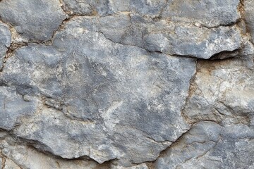 Fototapeta premium rugged weathered gray rock surface with layered cracks and rough textured stone, evoking a stark ancient and resilient feel