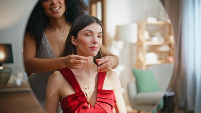 Two women proposing jewelry to friend looking mirror wearing red dress closeup.