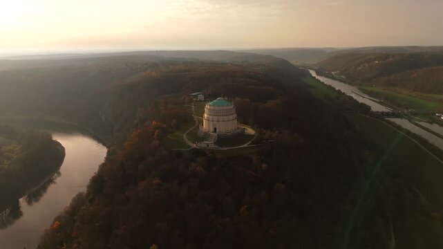 Herbstliche Luftaufnahme der Befreiungshalle Kelheim, Bayern, Deutschland. Von oben sieht man Donau, Donauenge, Main-Donau-Kanal und die bewaldeten Berghaenge des Altmuehltals im Abendlicht.