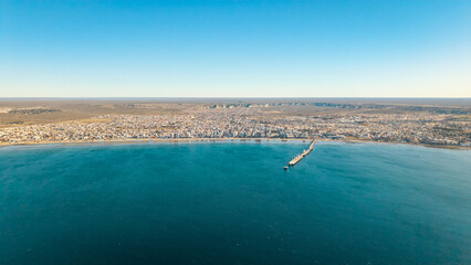 Panoramic aerial view of Puerto Madryn bay and Patagonian coastline under clear blue sky. © Marcio Eneas