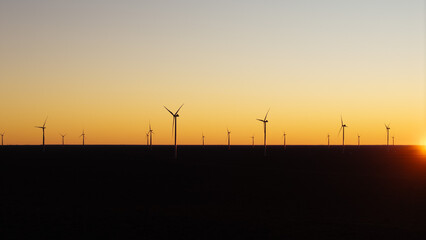 Minimal wind turbine silhouettes at sunset representing renewable energy and sustainable future. © Marcio Eneas
