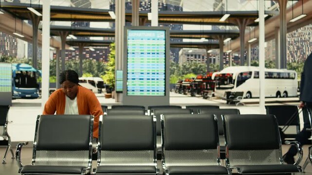 Passengers seated in bus terminal with backpacks and waiting for intercity coach, starting conversation with strangers and having a laugh before long-distance cross-country journey. Highway bus.