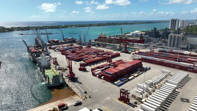 Aerial shot of industrial shipping terminal with stacks of cargo containers  at Port of Palm Beach Florida on a Bright Sunny Day (Partial Orbit)
