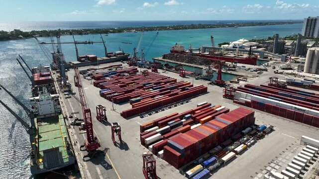 Drone shot of industrial shipping terminal with stacks of cargo containers  at Port of Palm Beach Florida on a Bright Sunny Day (Pull Back)
