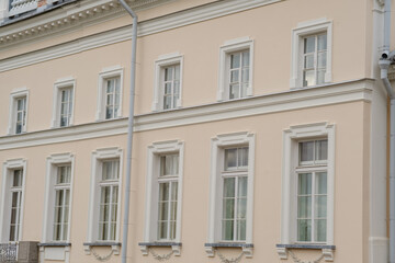 Obraz premium Historic building facade featuring several windows with decorative trim and a light pastel color scheme, showcasing classic architectural elements
