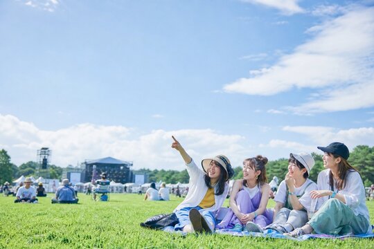 梅雨の晴れ間の野外音楽フェスで芝生を楽しむ日本人女性グループ