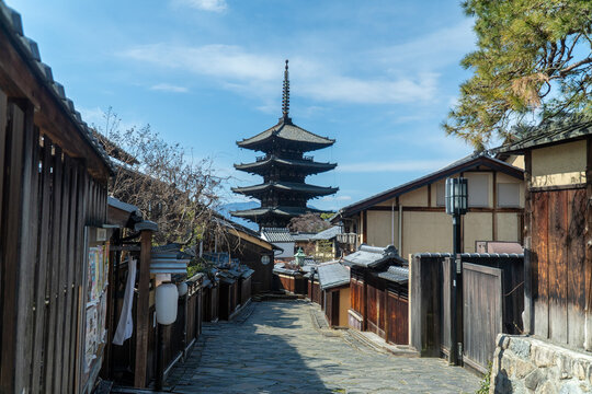 Yasaka Pagoda dominates the skyline at the end of a charming stone-paved street, framed by traditional wooden houses, capturing the historic essence of a Japanese neighborhood in Kyoto