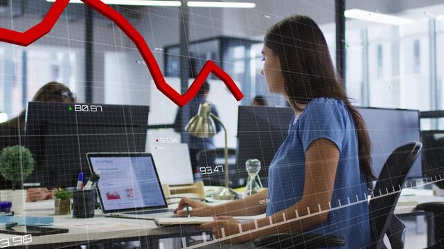 Woman typing at laptop in business office, data update causing red graph crossing laptop and face