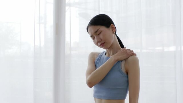 Asian Woman in Yoga Wear Touching Shoulder in Pain