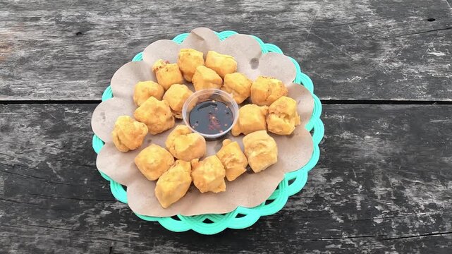 Crispy tofu (tahu crispy) in a paper bowl. Indonesian street food.