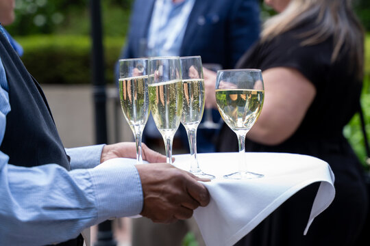 Waiter serving wine glasses at outdoor corporate event.