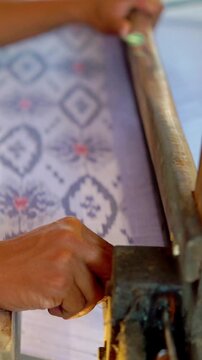 Making tenun ikat Bandar, Indonesia. An Indonesian woman weaving traditional fabric. Traditional weaving cotton in Indonesia.