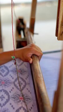 Making tenun ikat Bandar, Indonesia. An Indonesian woman weaving traditional fabric. Traditional weaving cotton in Indonesia.