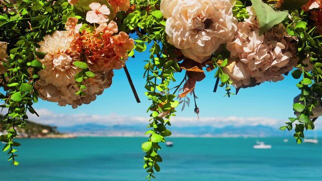 Decorative floral archway with hanging flowers overlooking beautiful turquoise sea view.