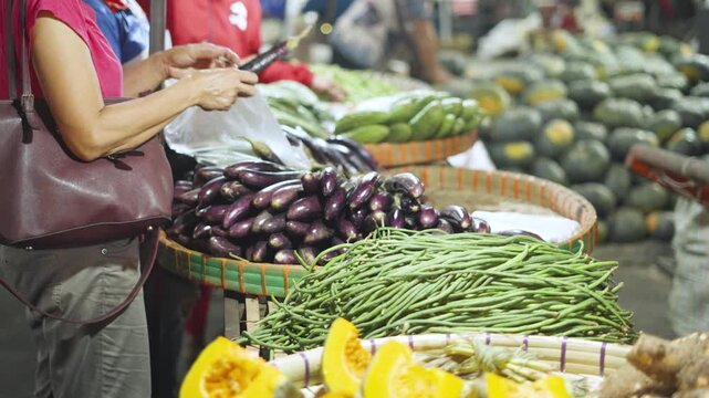 Customers Buying Yardlong Beans and Eggplants While Vendor Gives Change at Street Stall