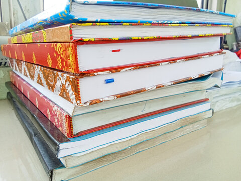 A neat stack of colorful hardcover books and notebooks on a desk.