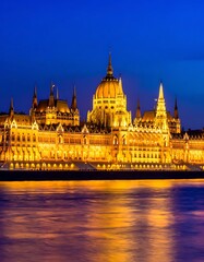 Obraz premium A blurred image of a large, ornate building with yellow lights reflecting off the water