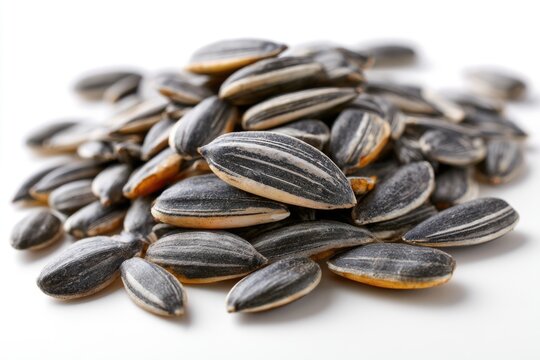A close-up of striped black and white sunflower seeds piled on a white surface.