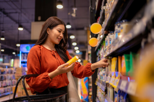 Woman choosing product from supermarket shelf for grocery shopping