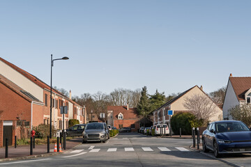 Fototapeta premium Suburban residential street in Ile de France, showing houses, parked cars, a crosswalk and quiet road layout in a Paris suburb, reflecting banlieue housing and everyday local urban planning.