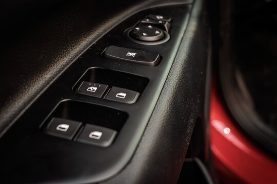 Close-up of a car interior door panel with electric window switches, mirror adjustment controls, and tactile buttons, emphasizing convenience features, ergonomics, and modern cabin design.