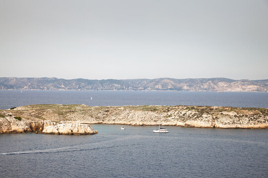 Boats anchored in Calanque de Ratonneau in the Iles du Frioul near Marseille, france with rocky islands, blue Mediterranean water and distant coastal hills, a symbol of sailing on the mediterranean.