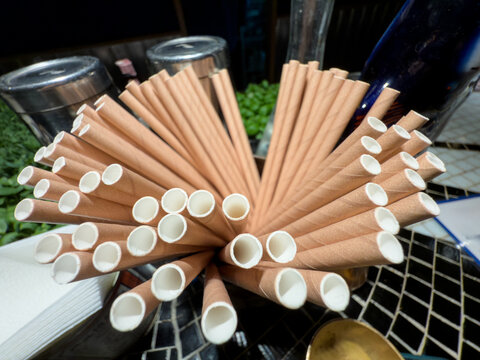 Kraft paper straws displayed on a bar counter, showing a cardboard alternative to plastic straws in food service and beverage settings.