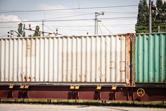 Grey shipping container loaded on a freight train wagon, showing rail cargo infrastructure and multimodal transport used for container logistics and goods movement.