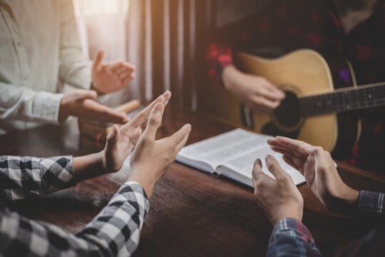 Group of christian sitting praying and worship God by playing guitar and sing a song together in home, musical devotion gathering, instrumental praise moment, christian worship meeting concept.