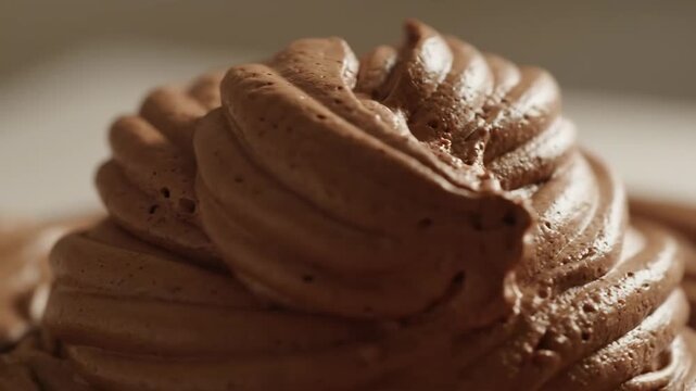 Extreme close-up macro shot of rich chocolate mousse frosting piped in swirls, showing delicious texture and detail