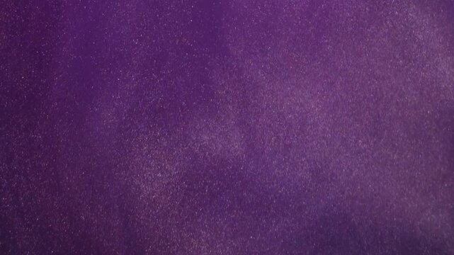 Floating ink. Wet texture. Defocused purple color grain paint in water chemical flow spreading on abstract art creative background.