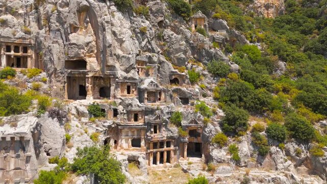 Demre, Turkey. Lycian rock-cut tombs of ancient Myra, temple-fronted facades carved into a sheer cliff face, close-up aerial view in bright summer light. Aerial View, Point of interest