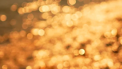 Fotobehang Zonsondergang Zee Bokeh light abstract, shimmering golden reflections on water, creating a beautiful warm background texture  © svetograph