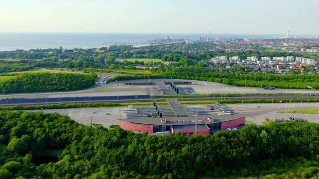Malmo, Sweden. Oresund Bridge toll plaza at Lernacken, Drone footage over the multi-lane payment gates and approaching highway, with the city and coast visible in the distance under clear summer skie