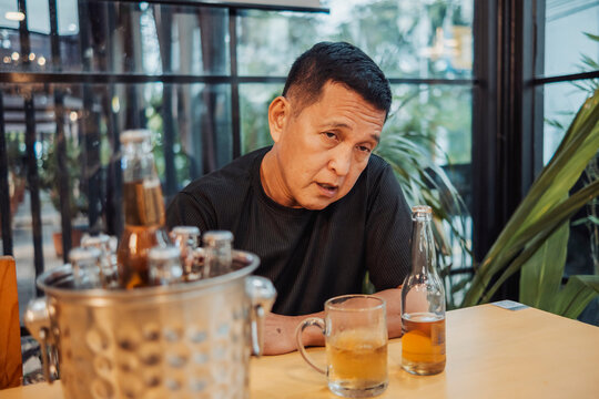 A drunk middle aged man staring at another person at the bar, appearing heavily intoxicated and confrontational