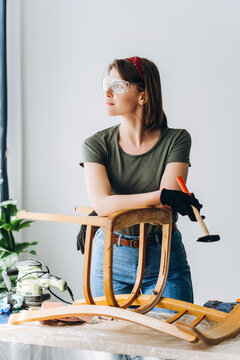 Beautiful woman renovating old wooden chair with tools