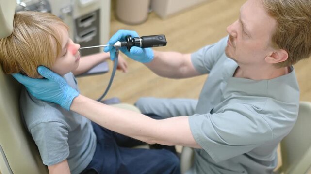 A male ENT doctor examines a patient with an endoscope in the office of a medical clinic. A professional otolaryngologist is at his workplace.