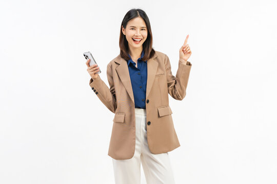 Smiling young Asian businesswoman using smartphone and pointing at mobile screen on white studio background.
