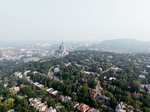 Hazy aerial view of Westmount and downtown Montreal skyline hidden behind smog and trees. c.