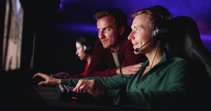 Young adult male gamers, friends discussing multiplayer game, talking, playing streaming videogames in modern gaming cybercafe club. Competitive e-sports match activity, digital entertainment, hobby
