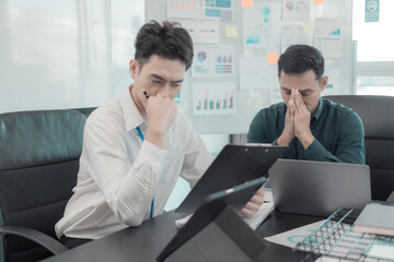 Obraz premium A business team stressed out reviewing financial reports during a meeting in a modern office setting reflects workplace pressures, financial issues, teamwork, and business decision-making.