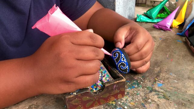 Close up of artisan hands meticulously painting traditional ceramic pottery with pink color cone, creative handmade crafts video